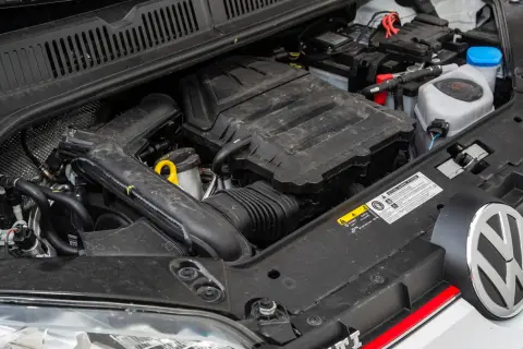 Silnik 1.0 TSI 110 KM w samochodzie Volkswagen. Widoczny akumulator, przewody i elementy osłony silnika.