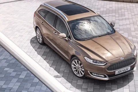 Elegancki, brązowy Ford Vignale kombi z panoramicznym dachem, lśniącym na tle nowoczesnej kostki brukowej.