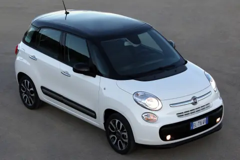 Biały Fiat 500L z czarnym dachem i felgami, zaparkowany na szarym podłożu.