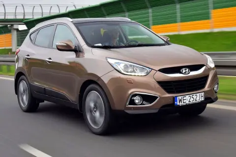 Brązowy Hyundai i35 na drodze, z zielono-żółtymi barierami dźwiękochłonnymi w tle.
