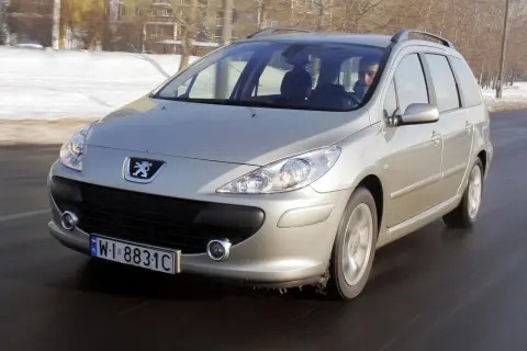 Srebrny Peugeot 307 1.6 HDI w wersji kombi jedzie po drodze, w tle zimowy krajobraz.