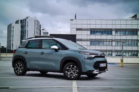 Szary Citroen C3 na parkingu przed nowoczesnymi budynkami. Wiele osób szuka **citroen c3 opinie** przed zakupem.