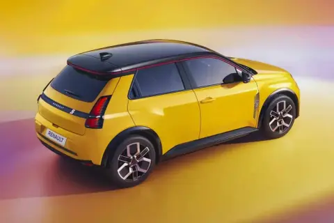 Nowe Renault 5 w jaskrawym żółtym kolorze z czarnym dachem i czerwonymi akcentami, prezentuje nowoczesny design.