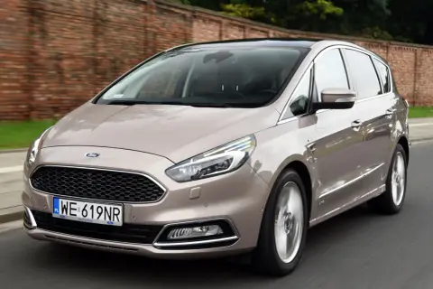 Beżowy Ford S-Max 2.0 TDCI w ruchu, z widocznym grillem i tablicą rejestracyjną WE 619NR.