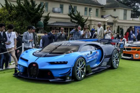 Niebieski Bugatti Chiron z numerem 16 na grillu, prezentowany na trawie, otoczony przez widzów robiących zdjęcia.