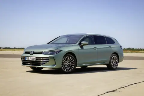 Nowy Volkswagen Passat B9 w kolorze zielonym, zaparkowany na betonowej nawierzchni, z błękitnym niebem w tle.