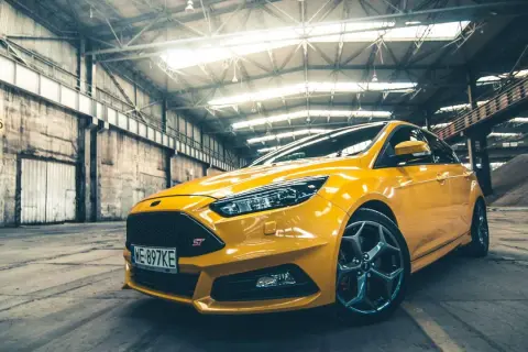 Żółty Ford Focus ST 2010 w hangarze, gotowy do akcji.