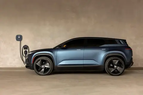 Niebieski Fisker SUV podłączony do ładowarki ściennej. Futurystyczny design i nowoczesna technologia.