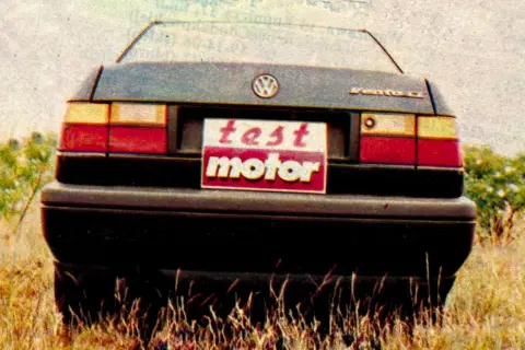 Tylna część Volkswagena Vento z tabliczką "test motor" na tle trawy i krzewów.