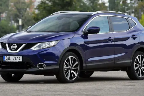Błękitny Nissan Qashqai 2. generacji z czarnym dachem i relingami, zaparkowany na drodze.