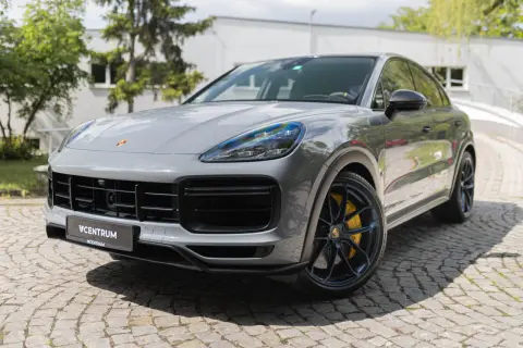 Szary Porsche Cayenne Turbo GT z żółtymi zaciskami hamulcowymi stoi na brukowanej nawierzchni.