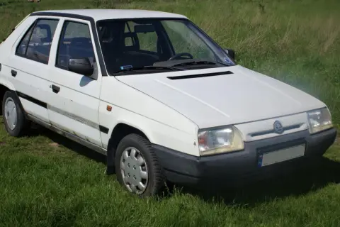 Biały Skoda Favorit stoi na trawie.