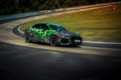 Rs3 Audi w zielono-czarnej kamuflażowej okleinie pędzi po torze wyścigowym.