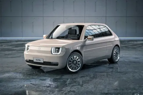 Nowoczesny polski fiat 126p w beżowym kolorze, z charakterystycznymi kwadratowymi światłami i stylowymi felgami, stoi na mokrej posadzce.