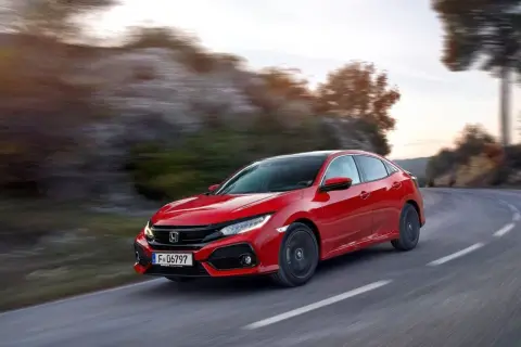 Czerwony Honda Civic 10 na zakręcie drogi, z rozmytym tłem gór i drzew.