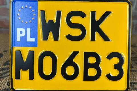Żółta tablica rejestracyjna z literami WSK i cyframi MO6B3. PL oznacza Polskę.