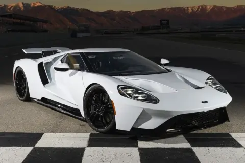 Biały Ford GT na torze wyścigowym, z górami w tle. Marzenie o osiągach i stylu, które wpływa na ford gt cena.