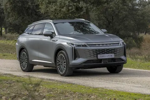 Szary OMODA 9 na drodze leśnej. Nowoczesny SUV z charakterystycznym grillem i światłami LED.