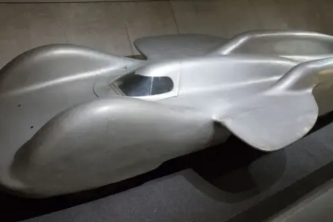 Srebrny, opływowy Mercedes T80, legendarny samochód wyścigowy, prezentuje swoje aerodynamiczne kształty.