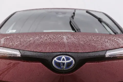 Czerwona Toyota z kroplami deszczu na masce i logo. Czy toyota ma ocynkowane blachy? Ta z pewnością jest dobrze zabezpieczona.