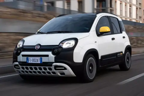 Biały Fiat Pandina z żółtymi lusterkami pędzi po drodze.