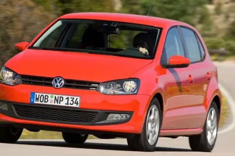 Czerwony vw polo 2010 na zakręcie drogi.