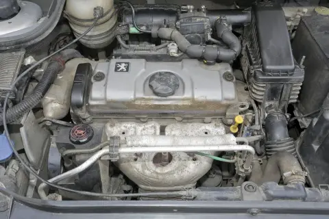 Silnik Peugeot 206 1.4 benzyna, widok z góry. Widać pokrywę zaworów z logo marki, elementy układu dolotowego i wydechowego.