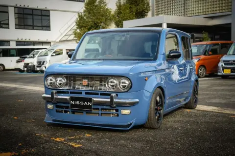 Niebieski Nissan Cube z chromowanymi zderzakami i grillem, obniżonym zawieszeniem i czarnymi felgami.