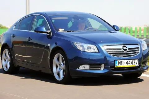 Niebieski Opel Insignia 2.0 CDTI w ruchu drogowym. Kierowca za kierownicą.