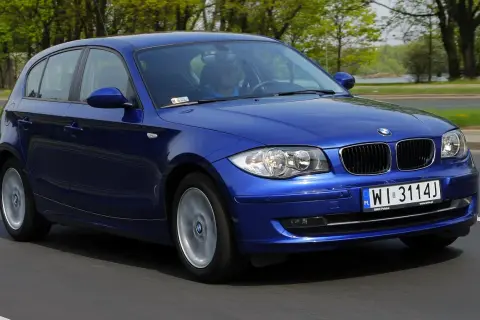Niebieskie BMW E87 116i w ruchu, z widocznym kierowcą i tablicą rejestracyjną WI 3114J.