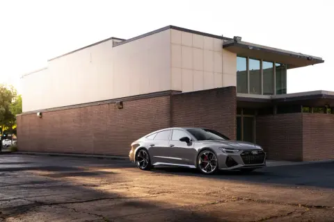 Elegancki, szary Audi RS7 zaparkowany przed nowoczesnym budynkiem.
