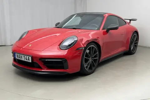 Czerwone Porsche 992 z widocznym uszkodzeniem na błotniku, stojące na szarym podłożu.