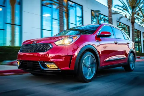 Czerwony Kia Niro w ruchu. Choć auto wygląda dynamicznie, warto pamiętać o jego potencjalnych wadach, np. ograniczonym zasięgu w wersji hybrydowej.