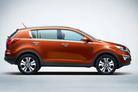Pomarańczowy Kia Sportage 1.7 CRDi z eleganckimi felgami stoi na jasnym tle.
