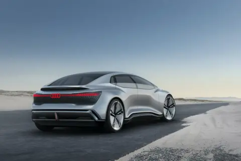 Srebrny Audi A9, futurystyczny koncept, jedzie po pustej drodze.