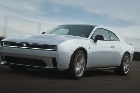 Biały Dodge Challenger Hellcat pędzi po torze wyścigowym, jego sylwetka jest dynamiczna i agresywna.