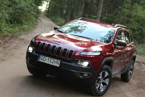 Czerwony Jeep Cherokee Trailhawk na leśnej, piaszczystej drodze. Gotowy na przygodę.