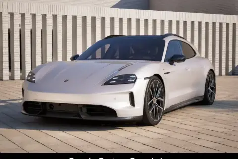 Biały Porsche Taycan Cross Turismo prezentuje się elegancko na tle nowoczesnej architektury.