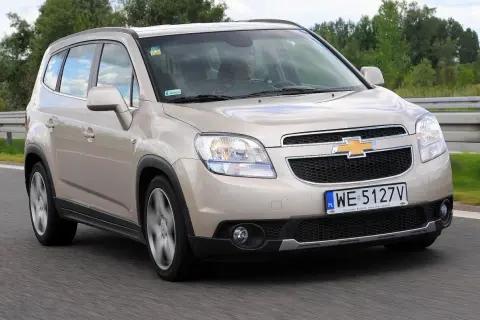 Złoty Chevrolet Orlando na drodze. Kierowca w środku. Wiele osób szuka chevrolet orlando opinie, ten samochód może być dobrym wyborem.