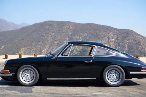 Klasyczny czarny Porsche 912 na tle górskich krajobrazów.
