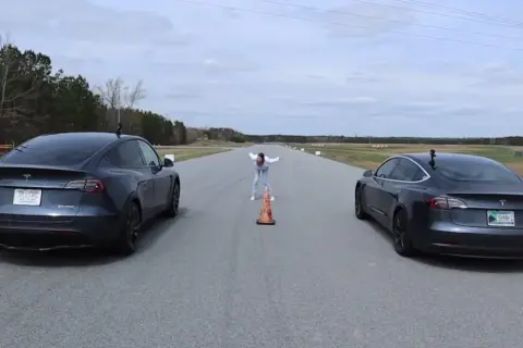 Dwa modele Tesla Model 3 i Model Y stoją na torze wyścigowym, gotowe do startu.
