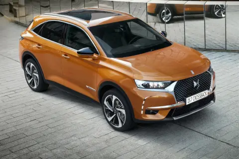 Pomarańczowy Citroën DS7 Crossback lśni na tle lustrzanej ściany. Elegancki SUV prezentuje swoje nowoczesne linie.