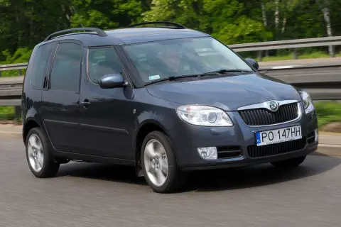Ciemnoszara Skoda Roomster jedzie po drodze, za kierownicą siedzi mężczyzna.