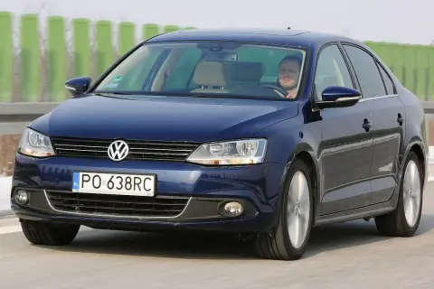 Ciemnoniebieski VW Jetta MK6 jedzie po autostradzie. Kierowca patrzy przed siebie.