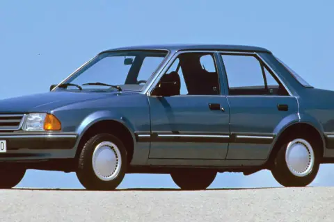 Niebieski Ford Orion z lat 80. na tle błękitnego nieba. Klasyk z przeszłości, który wciąż budzi nostalgię.