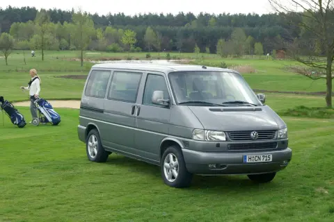 Szary VW T4 2.5 TDI 102KM na polu golfowym. Kobieta z kijami golfowymi obok.