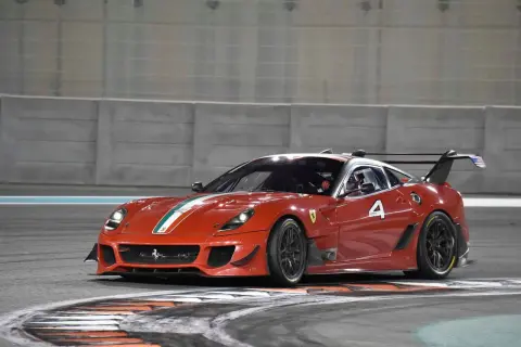 Czerwony Ferrari FXX K z numerem 4 na torze wyścigowym, gotowy do pokonania kolejnego zakrętu.
