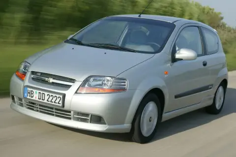 Srebrny Chevrolet Kalos w wersji 3-drzwiowej porusza się po drodze.