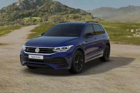Niebieski Volkswagen Tiguan R-Line na tle krajobrazu. Wiele osób szuka volkswagen tiguan opinie przed zakupem.