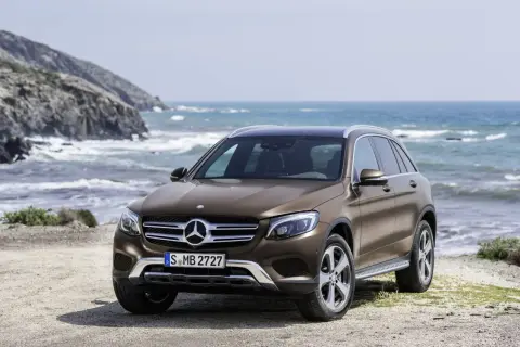Brązowy, używany Mercedes GLC z salonu na tle morskiego krajobrazu. Idealny na wakacyjne wyprawy.